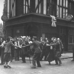 Injured musicians play while civilians and soldiers do an impromptu dance in the streets on VE Day to celebrate the end of WWII in Europe